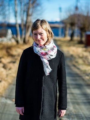 Merete Hoel Roaldsnes står på en landevei og smiler.