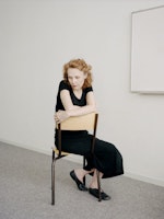 Kaija Saariaho sitter på en stol i et hvitt rom