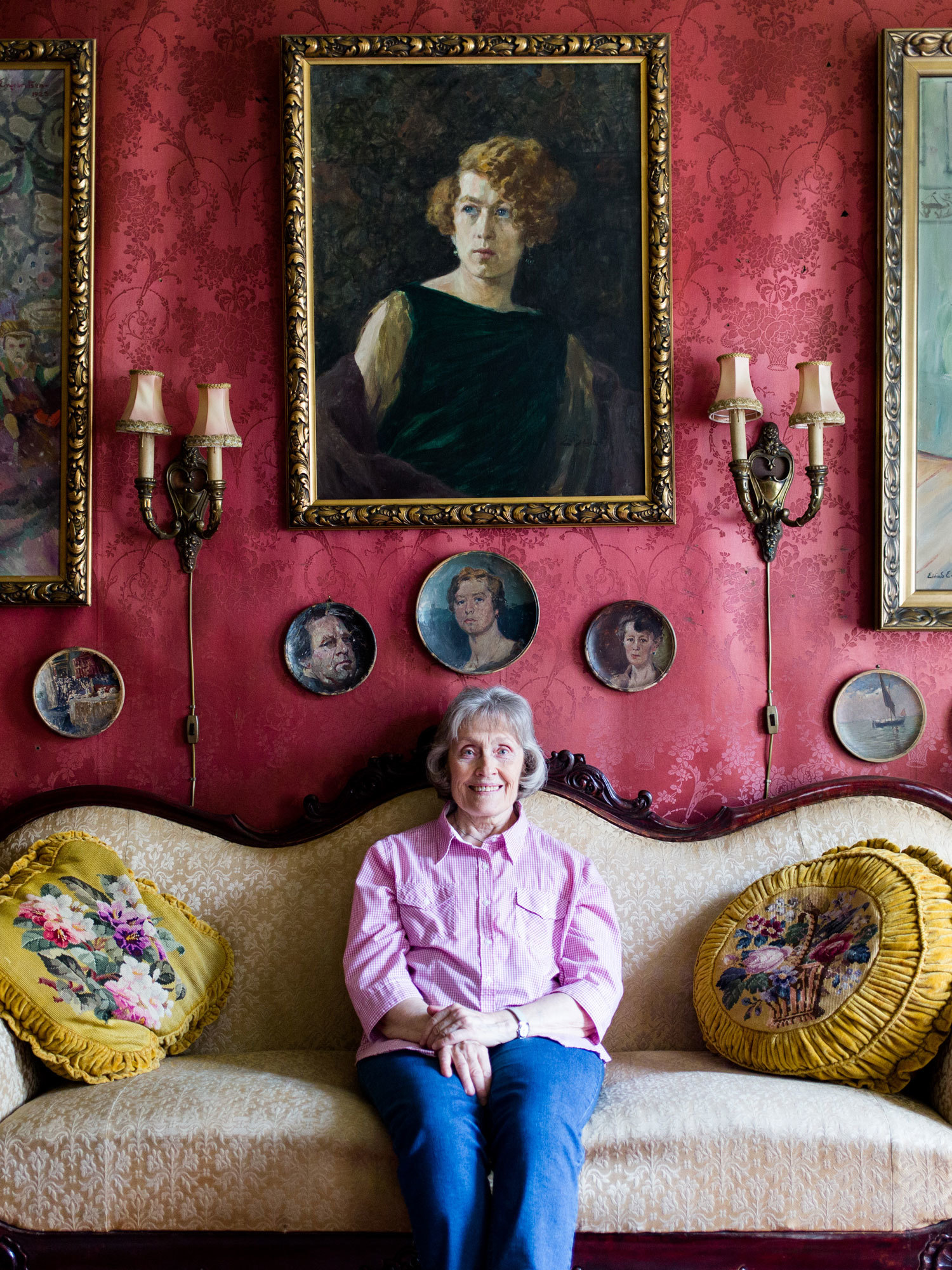 Liv Glaser sitter på en lys sofa i et rødt rom i Lallakroken