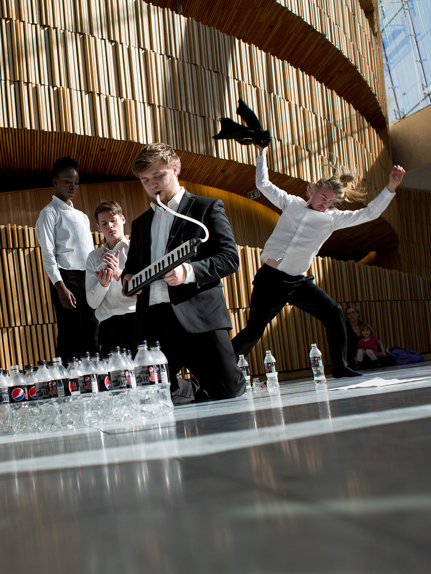 Composition students play melodica and moves around in the foyer of the Opera House.
