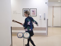 Musikkterapeut Monika Overå bærer på trommer og gitar inne på sykehus