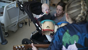 Musikkterapeut Monika Overå spiller gitar for baby og mamma på sykehus