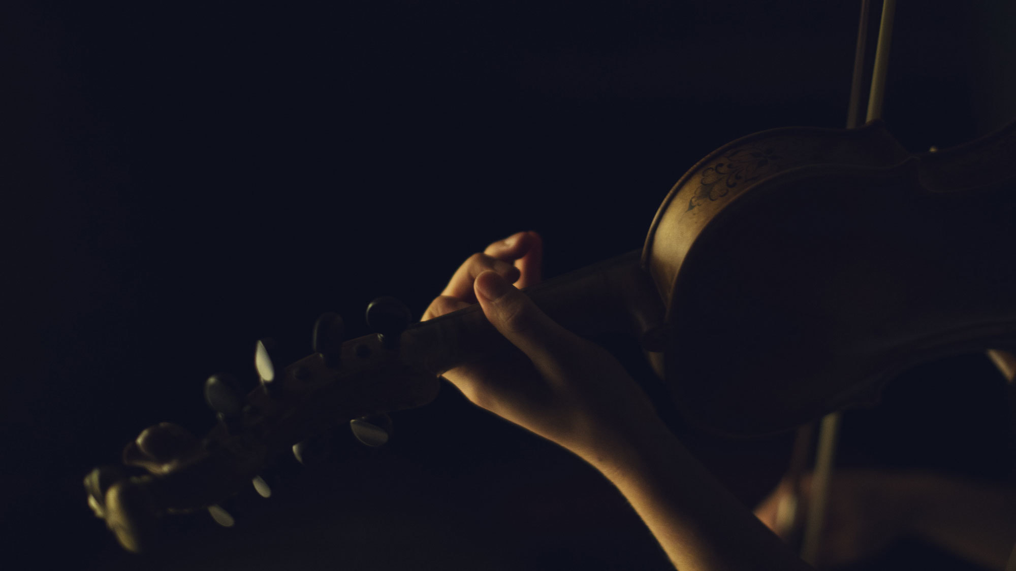 Hender som spiller hardingfele i mørket