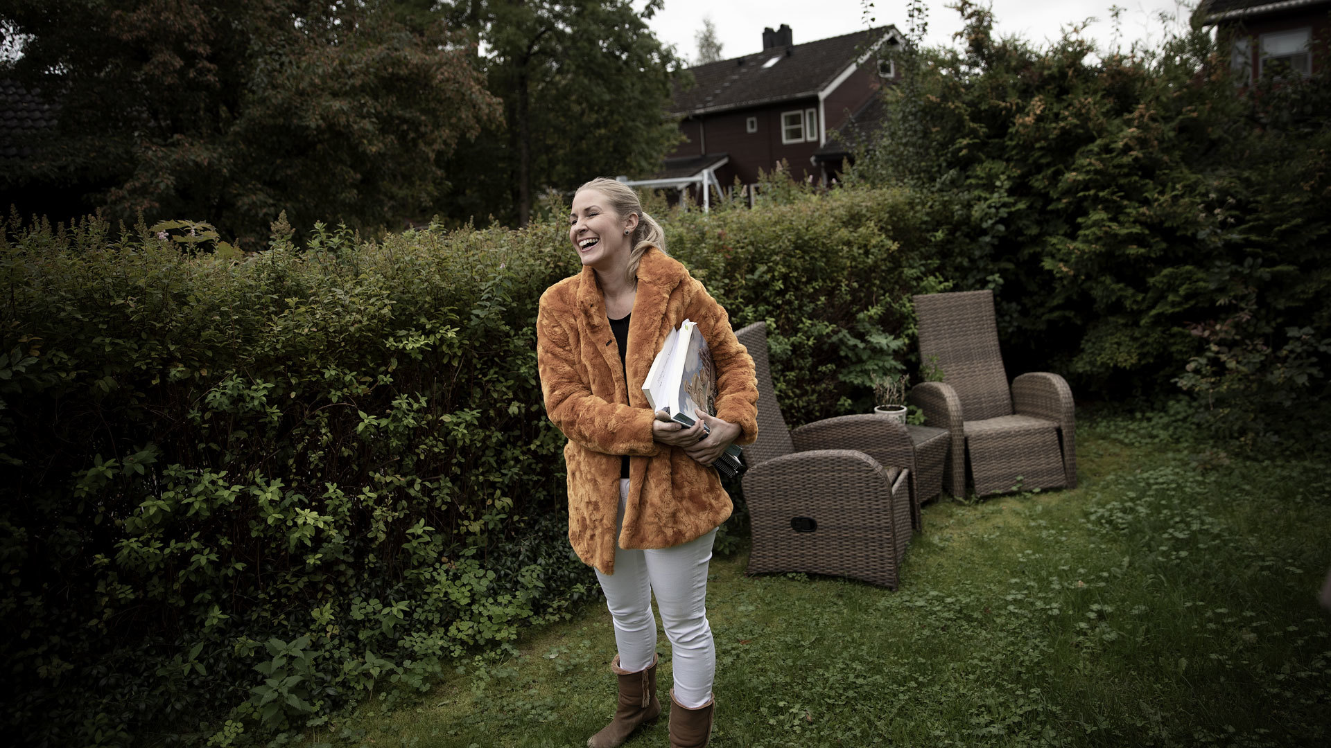 Cathrine Winnes står i hagen sin med partitur og dirigentpinne