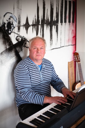 Homeside-deltaker Harald spiller piano foran vegg med trompetspiller-veggmaleri