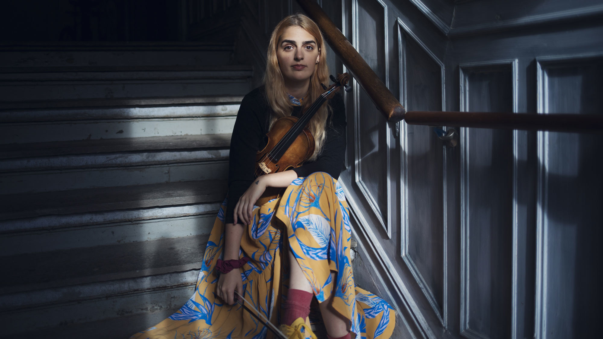 Larissa Terescenko sitter i trapp med fiolinen på fanget