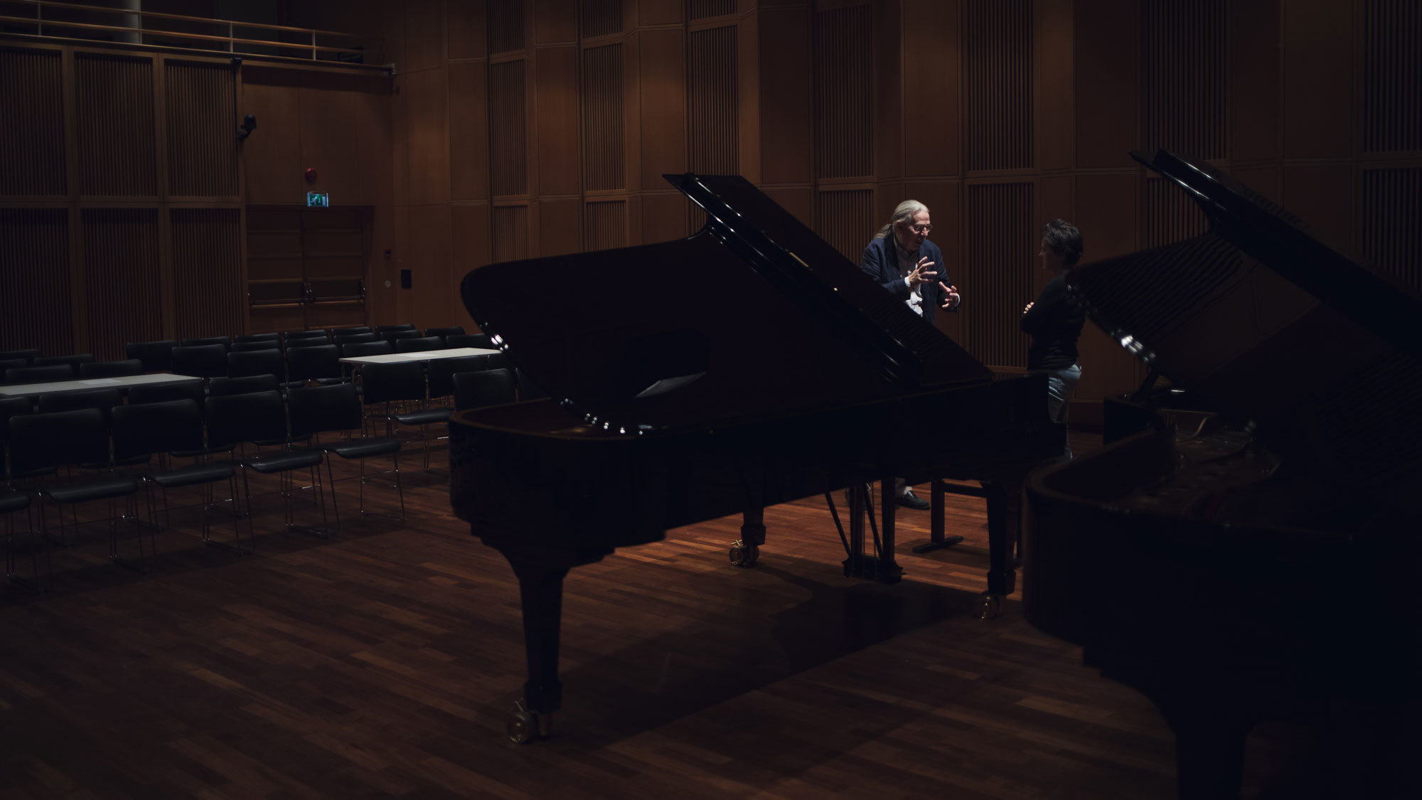 Petter Andersen snakker med noen i Levinsalen, bak flygelet