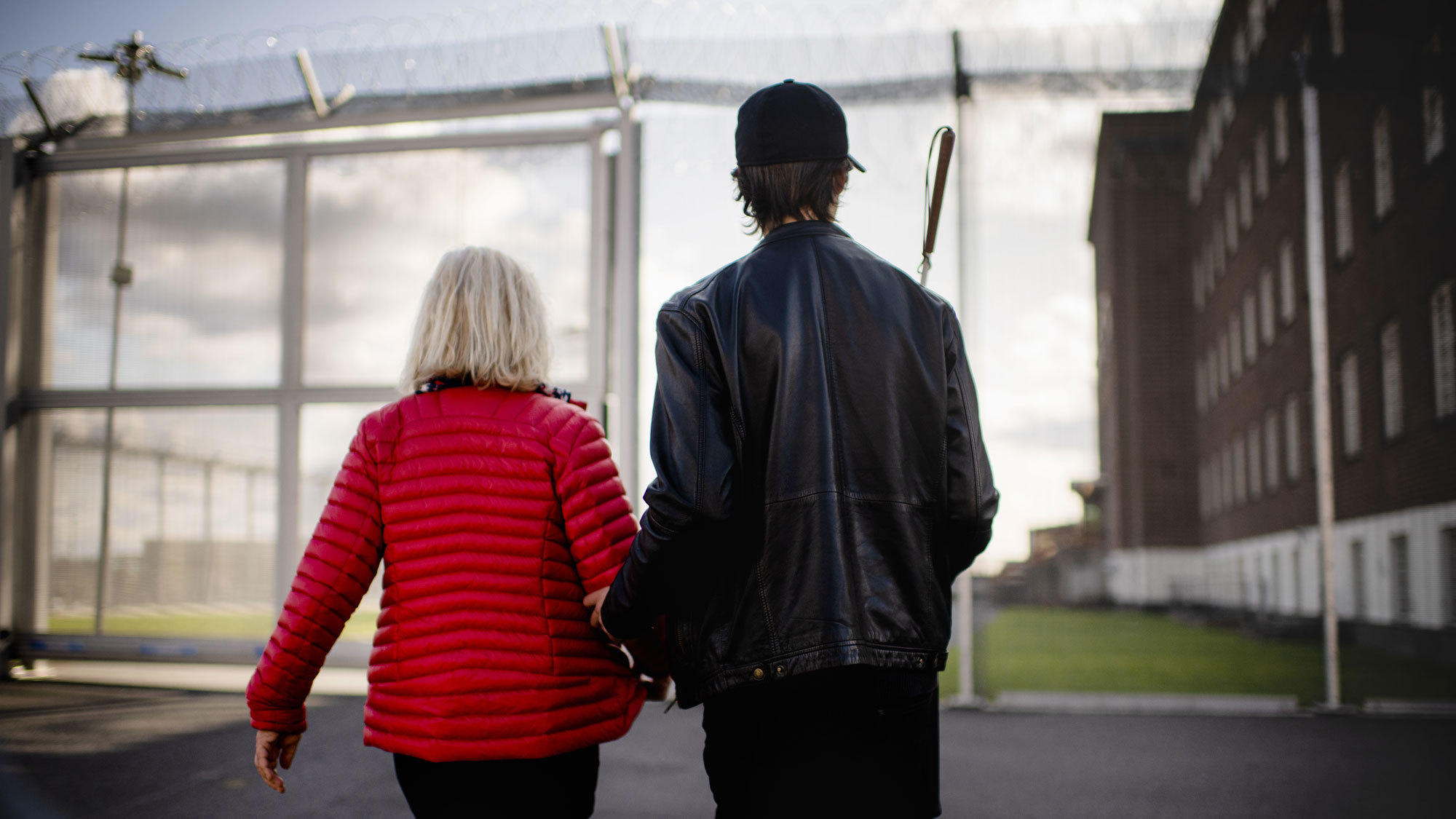 The backs of Bente Almås and Thomas Tvedt heading towards the gate of Ila Prison.