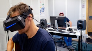 Musiker med VR_briller i forgrunnen, tekniker/musiker i bakgrunnen foran PC-skjerm