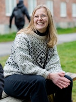 Andrine Erdal sitter på et parkbord og smiler