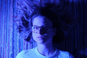 Blåaktig bilde av Astrid Solberg som ligger på et teppe med håret ut