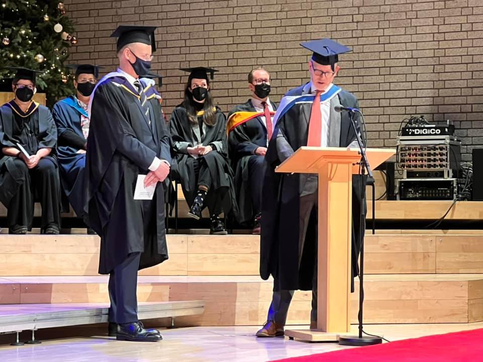 Peter Tornquist tildeles Honorary Fellowship ved RNCM, iført kappe, lue og munnbind