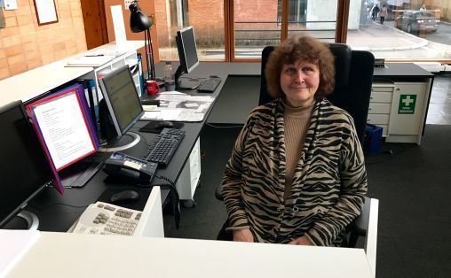 Vera Scott Stenersen sitter i resepsjonen på NMH og smiler.
