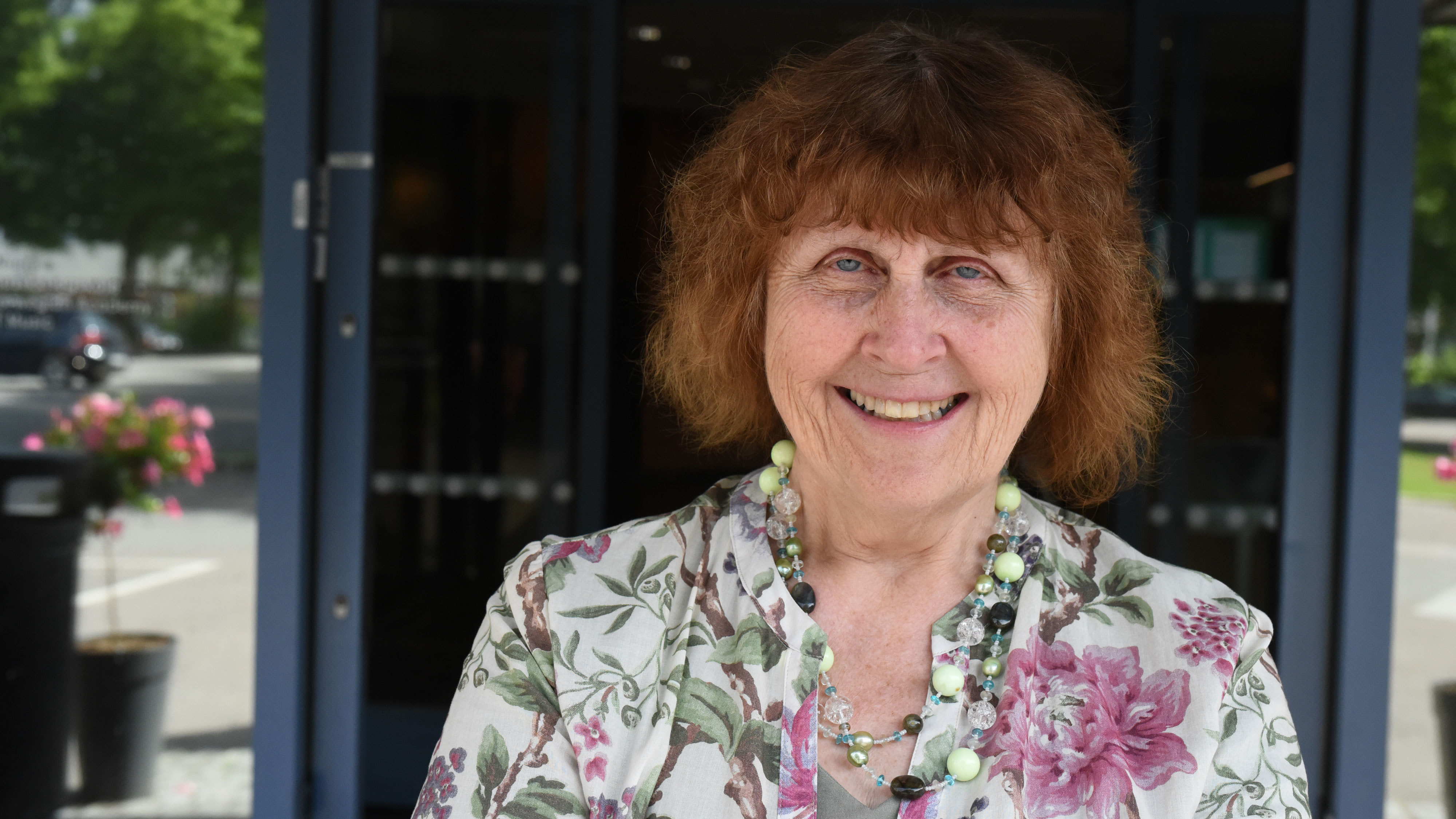 Vera Scott Stenersen står foran inngangen til NMH og smiler.