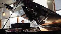 Pianist titter opp bak et stort, åpent flygel