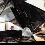Pianist titter opp bak et stort, åpent flygel