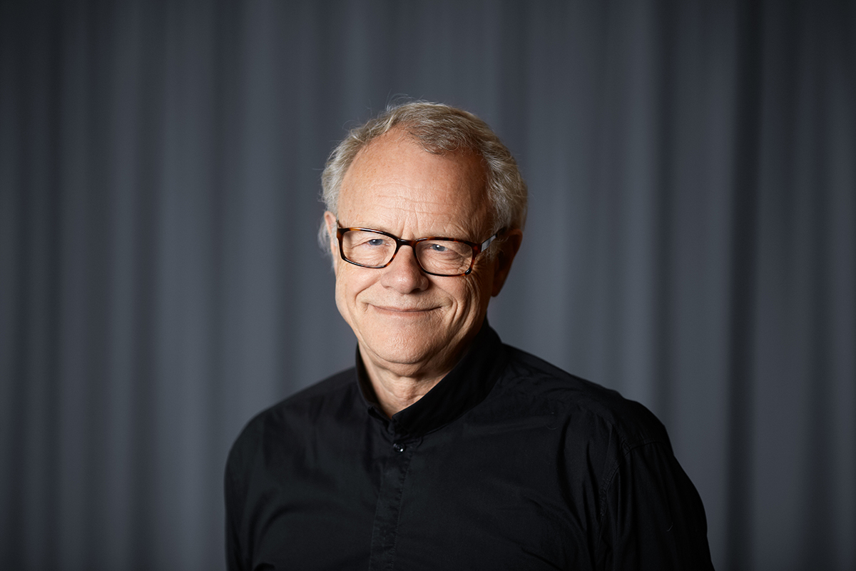 Portrettbilde av Bjørn Kruse foran grå gardin.