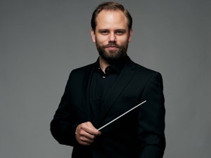 Portrett av Daniel Reith med dirigentpinne i hånden.