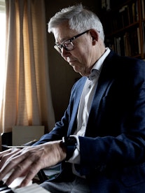Harald Herresthal som sitter ved orgelet og spiller, med bokhyller bak seg.