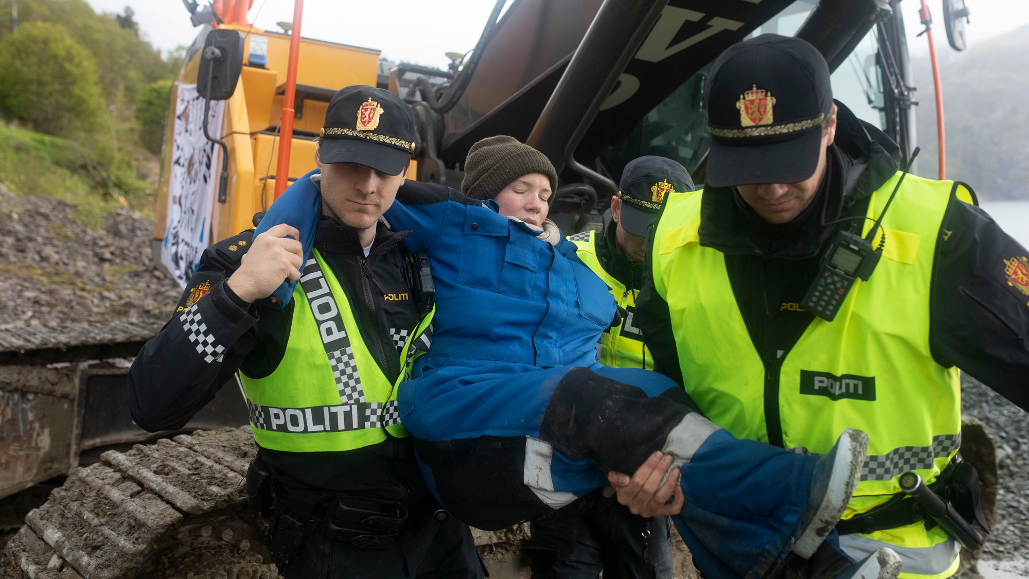 Hilja Løvvik blir båret vekk fra en gravemaskin av politiet.