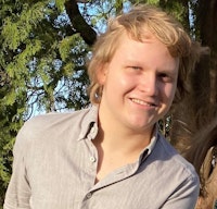 Mathias Kråkenes i lys skjorte foran grønne grener.