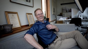 Peter Tornquist sitter i sofaen på rektorkontoret og ler.
