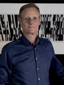 Portrett av Peter Tornquist foran et moderne kunstverk i svart-hvitt.