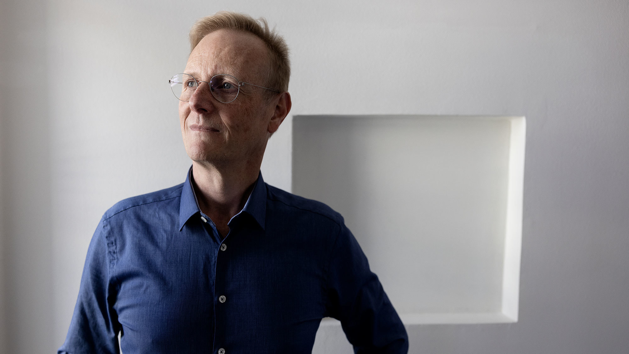 Peter Tornquist foran hvit vegg med en firkantet form på veggen.