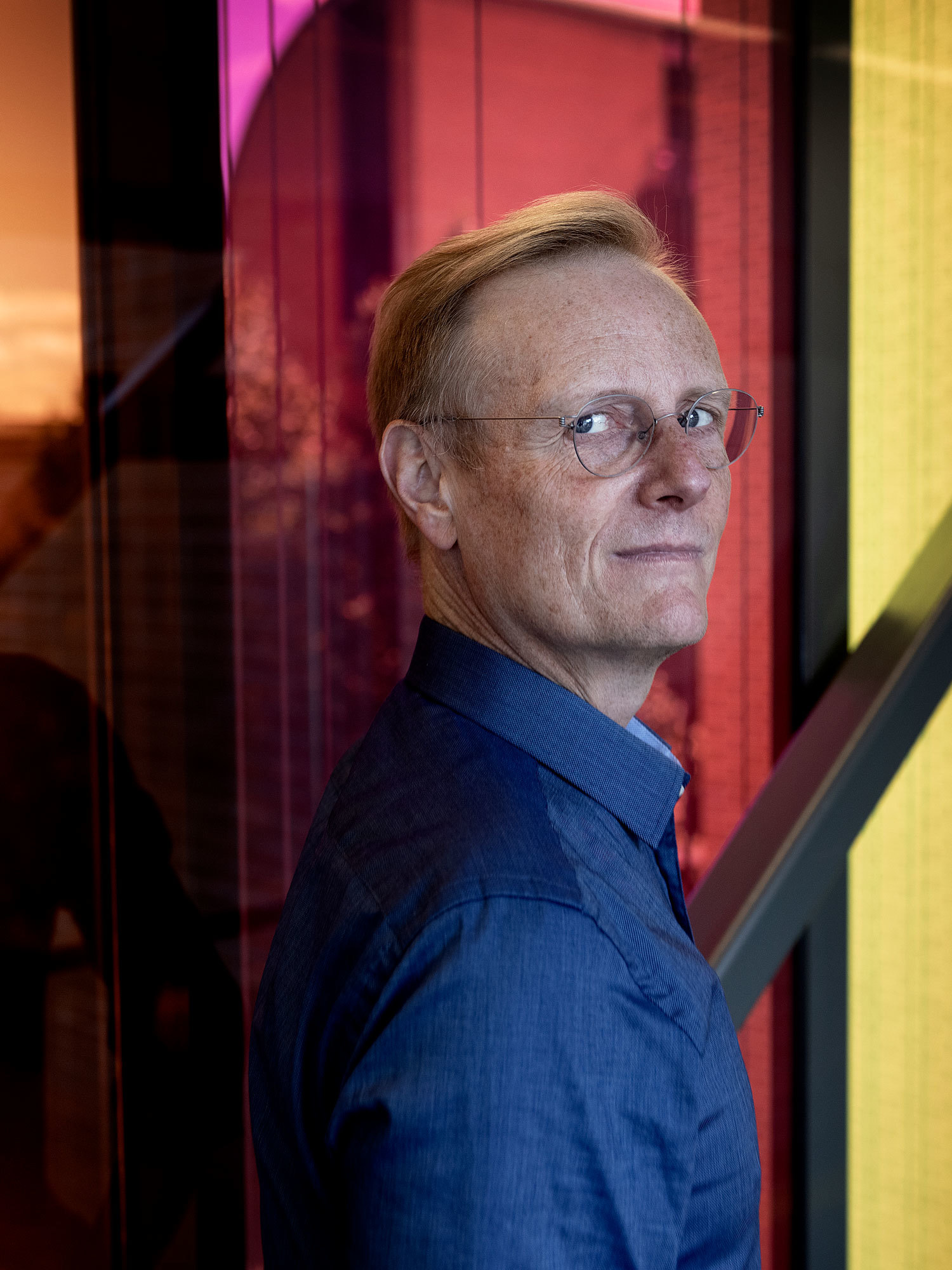 Peter Tornquist står foran de fargerike glassene på broen mellom 1. og 2. hus på NMH.