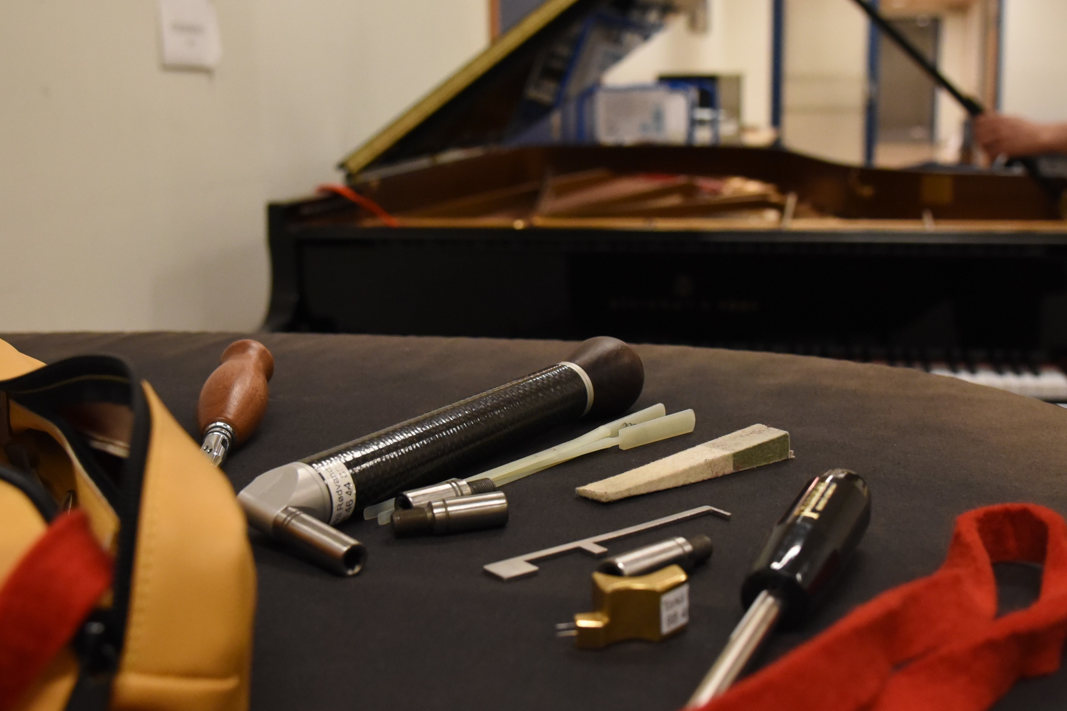 Verktøy for pianostemming på svart underlag, flygel i bakgrunnen