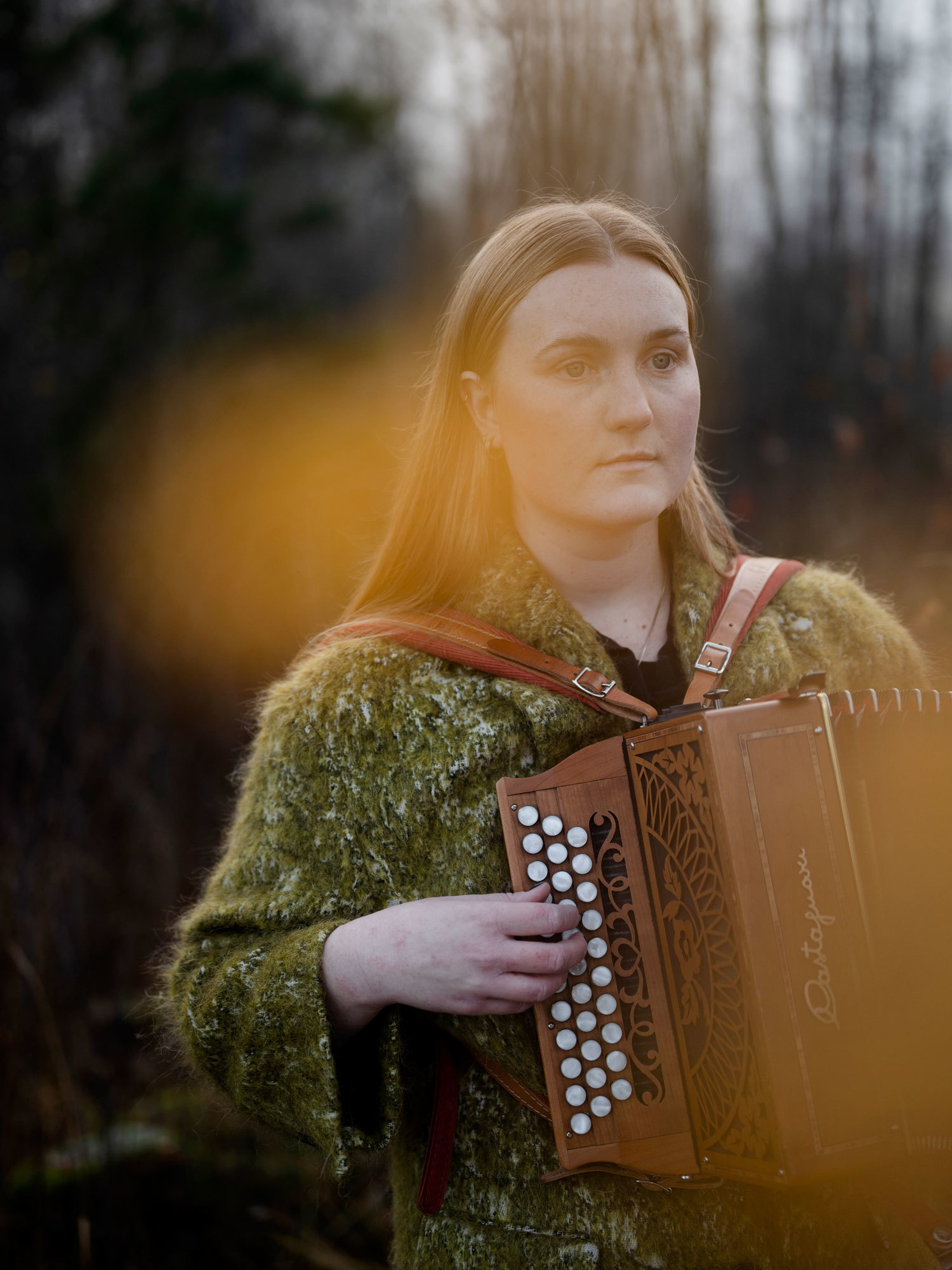 Amalie Kinsarvik Tvilde stirrer ut i luften mens hun spiller torader mellom trærne.