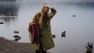 Amalie Kinsarvik Tvilde står med toraderen og ser utover et vann, mens hun rusker seg i håret.