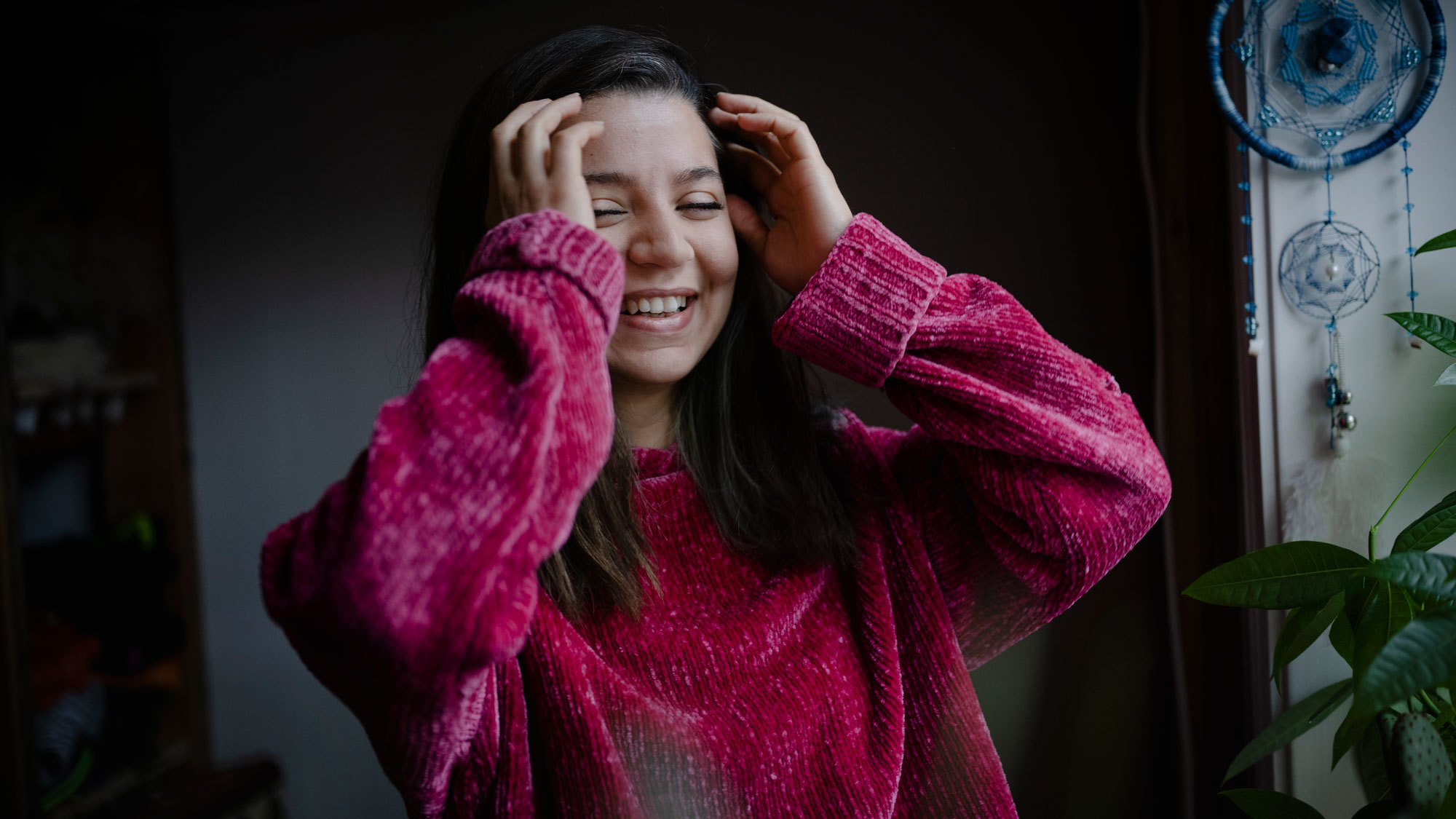 Nawar Alnaddaf som ler og har på rosa genser og tar seg selv i håret.