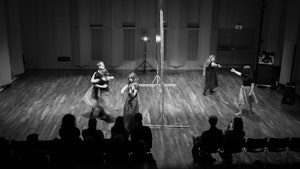 Svarthvittbilde av folkemusikere som spiller fele og danser i Levinsalen under Ultimafestivalen 2023.