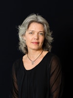 Portrett av en alvorlig Astrid Kvalbein foran svart bakgrunn.