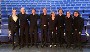Alle dirigentene på NMH i 2023, står i svarte klær foran de blå stolene i Lindemansalen.