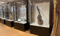En harpe og flere montre med instrumenter slik de står i biblioteket i dag.
