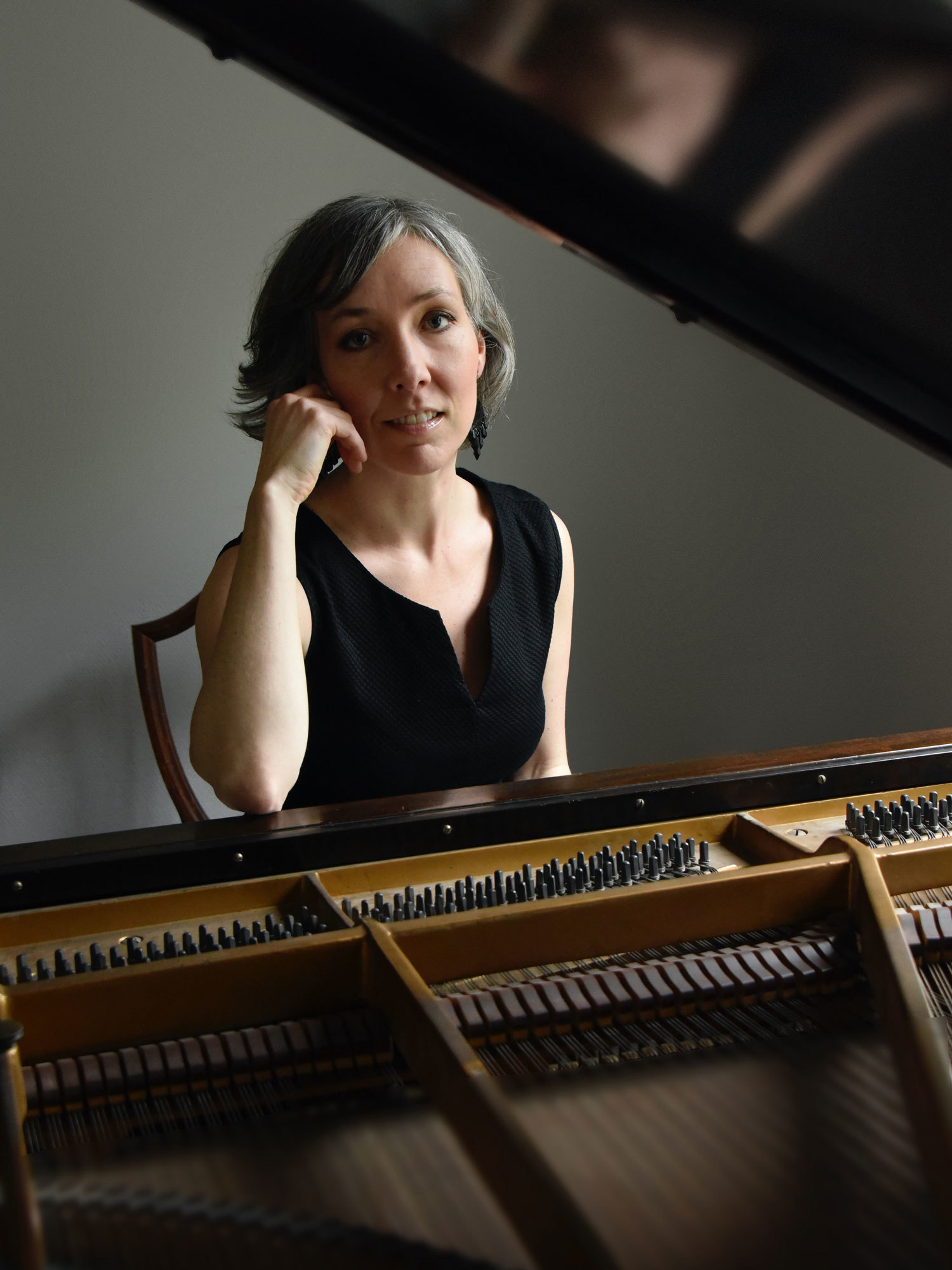 Portrett av Lina Braaten bak et flygel. Braaten er uni­ver­si­tets­lek­tor ved NMH og leder Fagseksjon for klaver, akkompagnement, gitar og akkordeon.