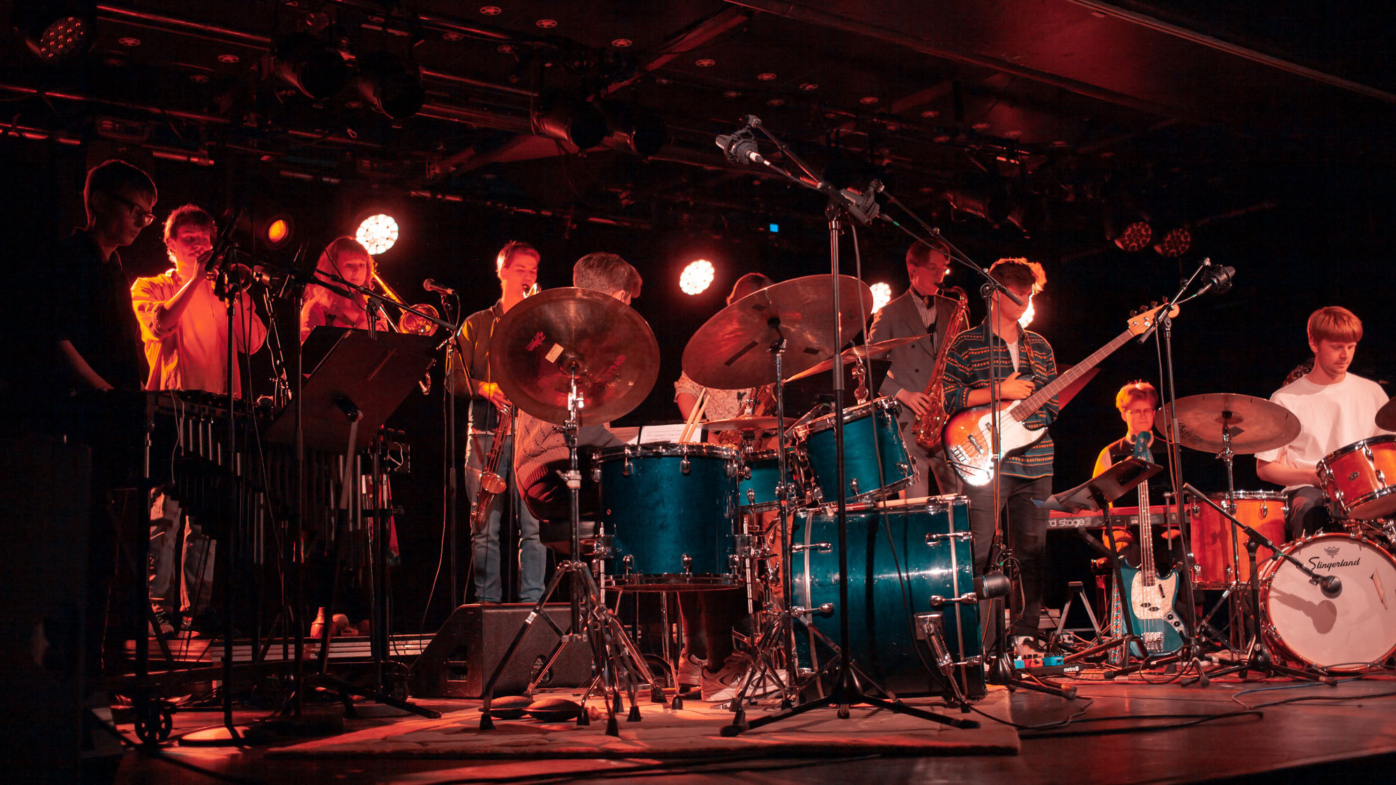 Stette Collective på scenen under konsert, i rødaktig lys.