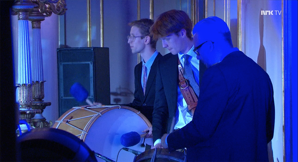 Tre trommeslagere i blått lys inne på slottet.