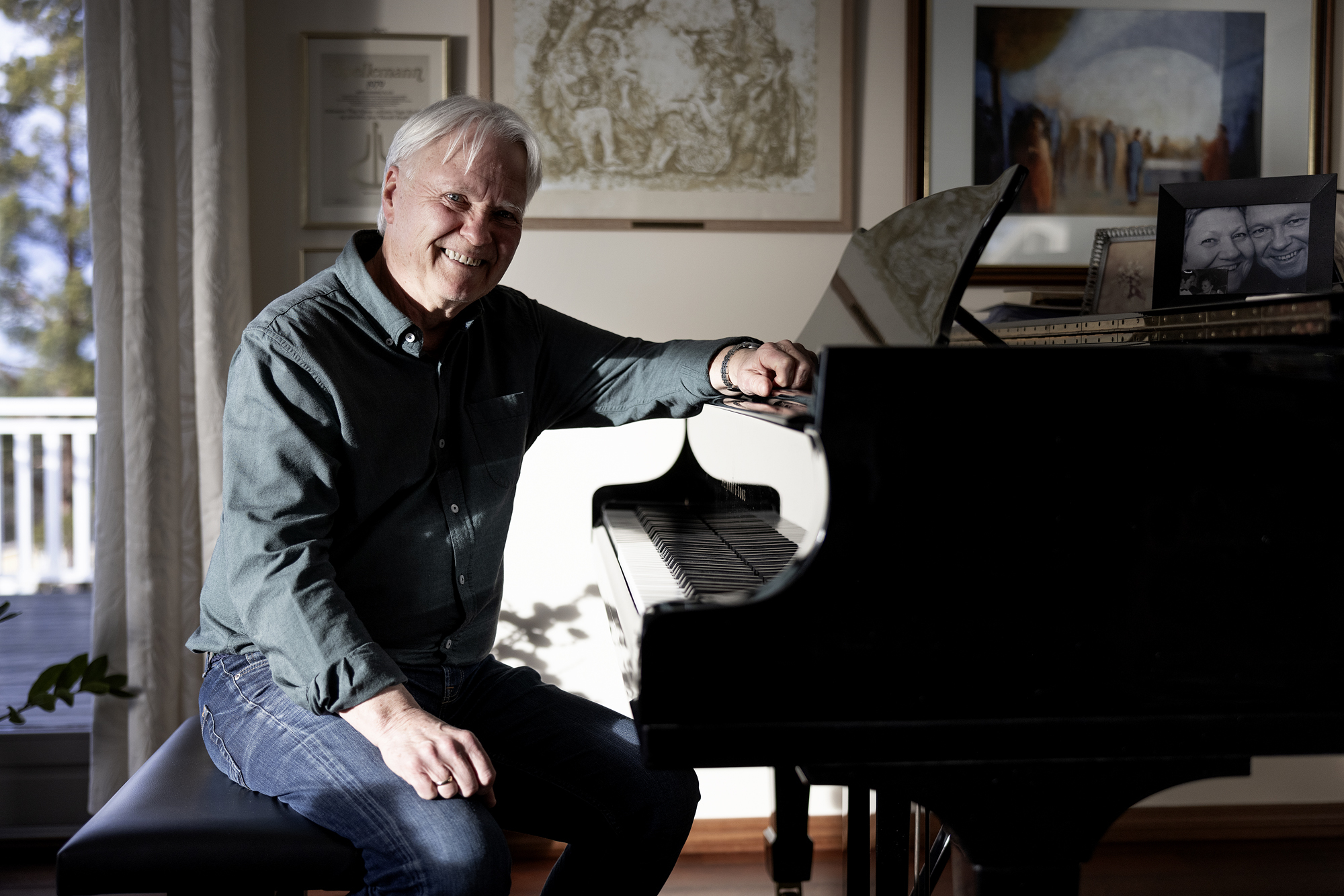 Jens Harald Bratlie smiler mens han lener seg over flygelet.