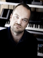 Portrett av Morten Qvenild foran tangentinstrument. Alvorlig uttrykk.