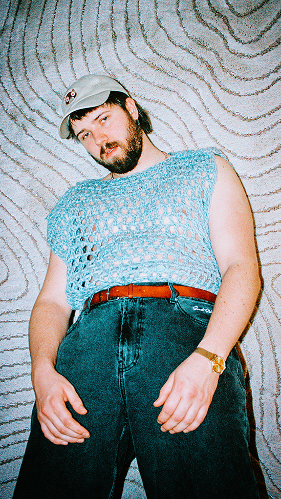 Portrett av Tobias Grønborg fra froskeperspektiv foran mønstrete vegg.