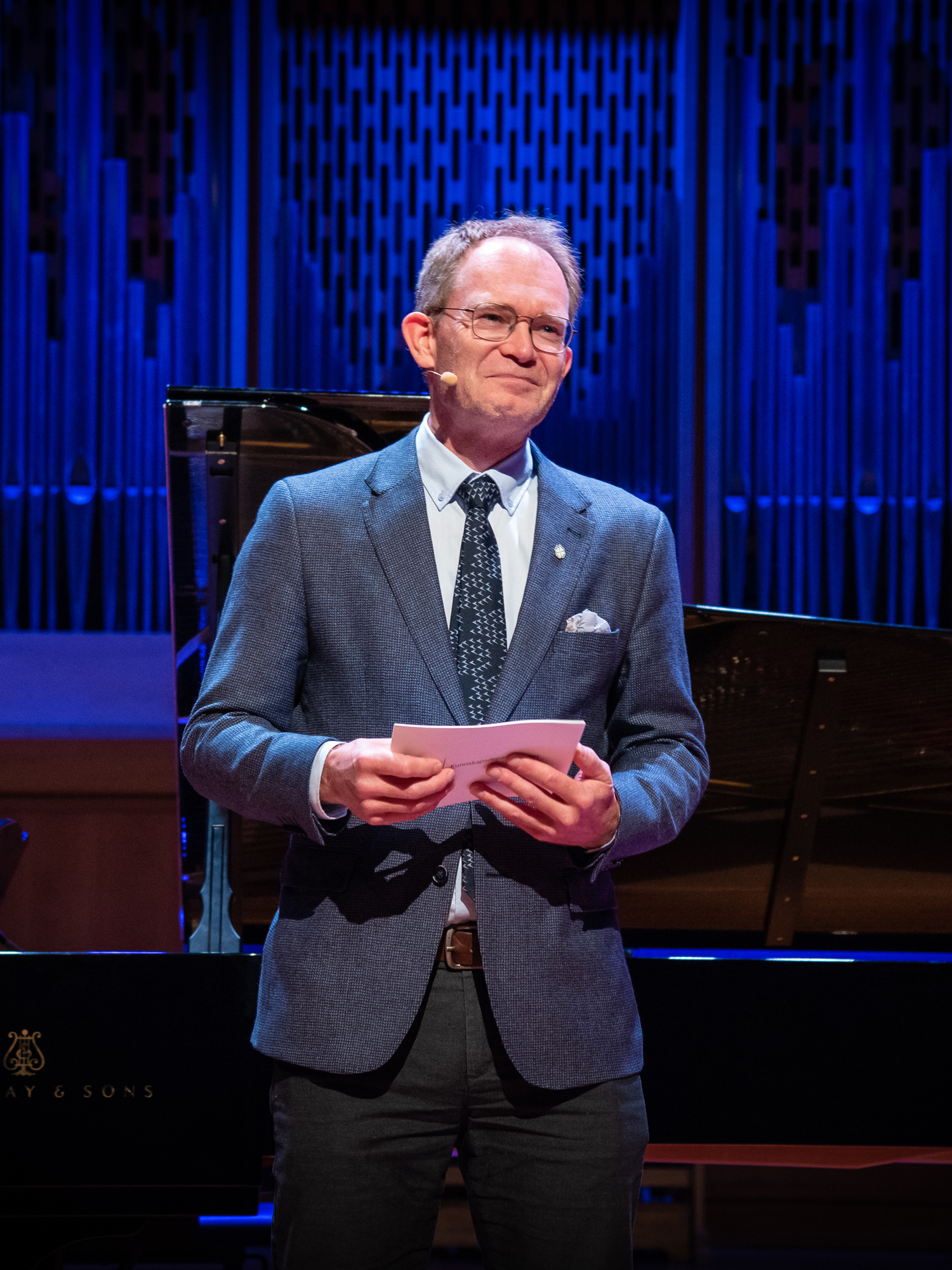 Oddmund Hole taler i Lindemansalen foran blått opplyst orgel.