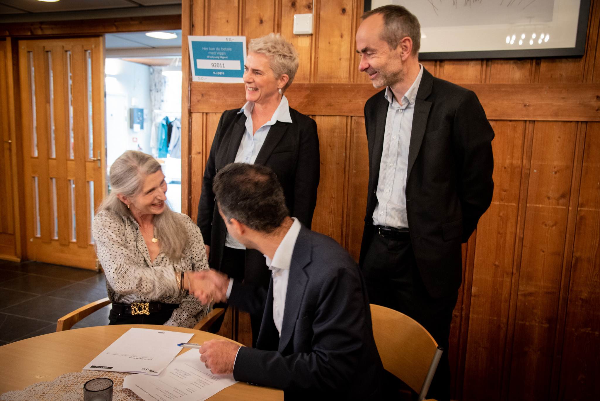 Kristel Skorge og Saliba Korkunc skriver under avtale og tar hverandre i hånden, om demenskor i Oslo. Karette Stensæth og Øyvind Håbrekke står bak dem.
