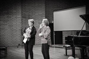 Hilde Ringlund og Jorunn Marie Bratlie står i Lindemansalen og smiler.
