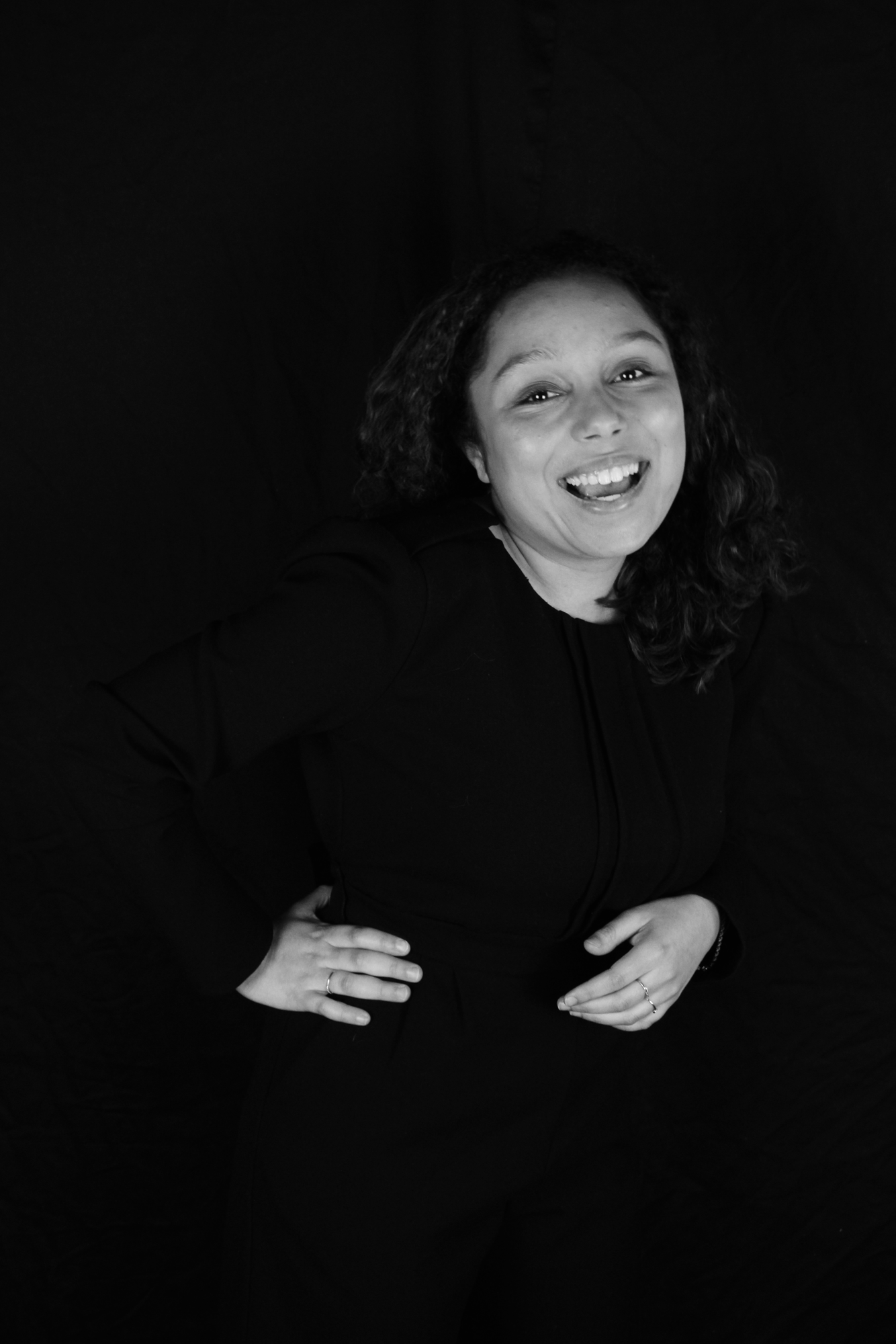 Lucie Camps står med hendene i siden i et mørkt rom og smiler.