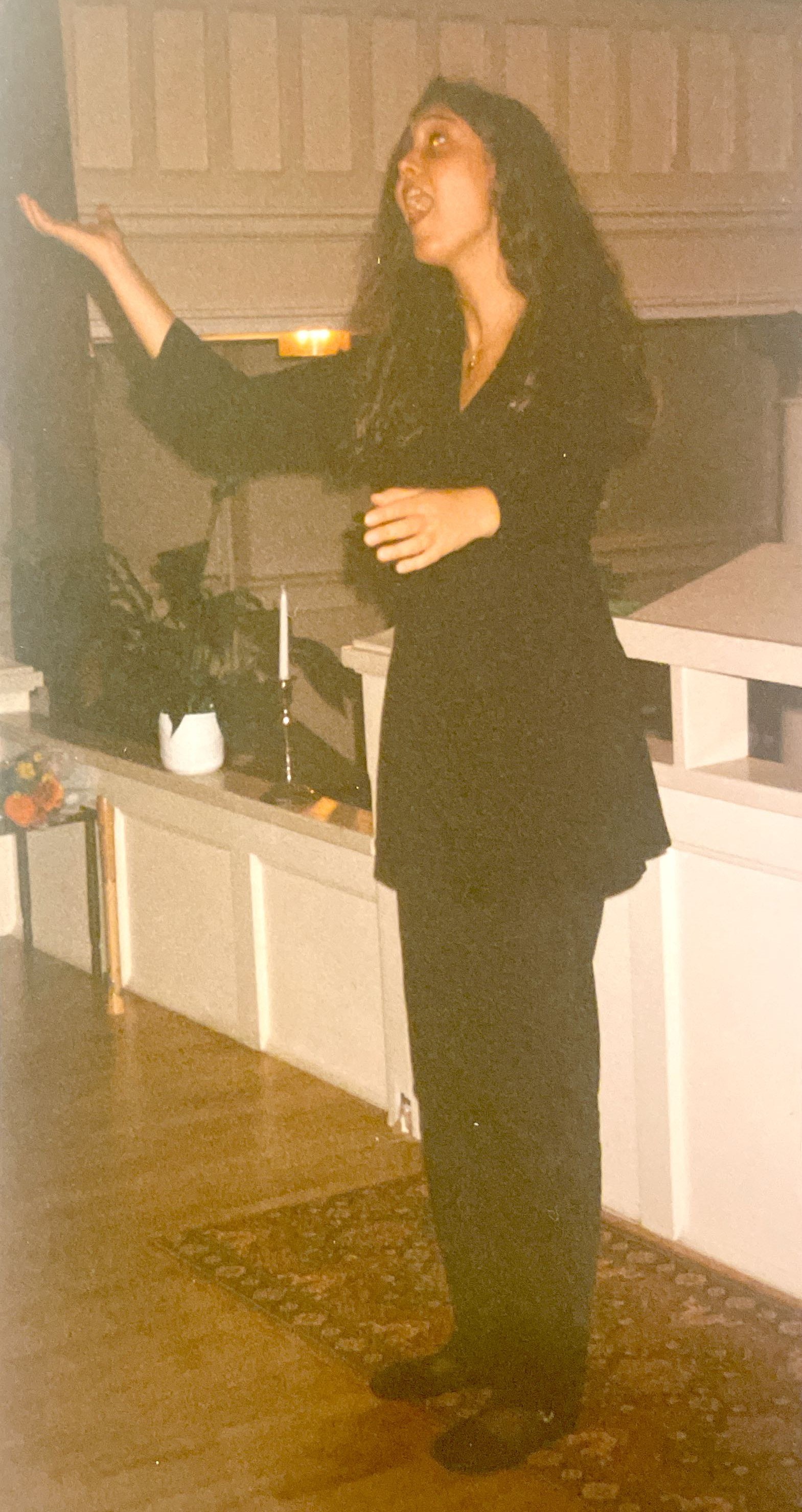 Ung kvinne står på et galleri i en kirke og dirigerer.