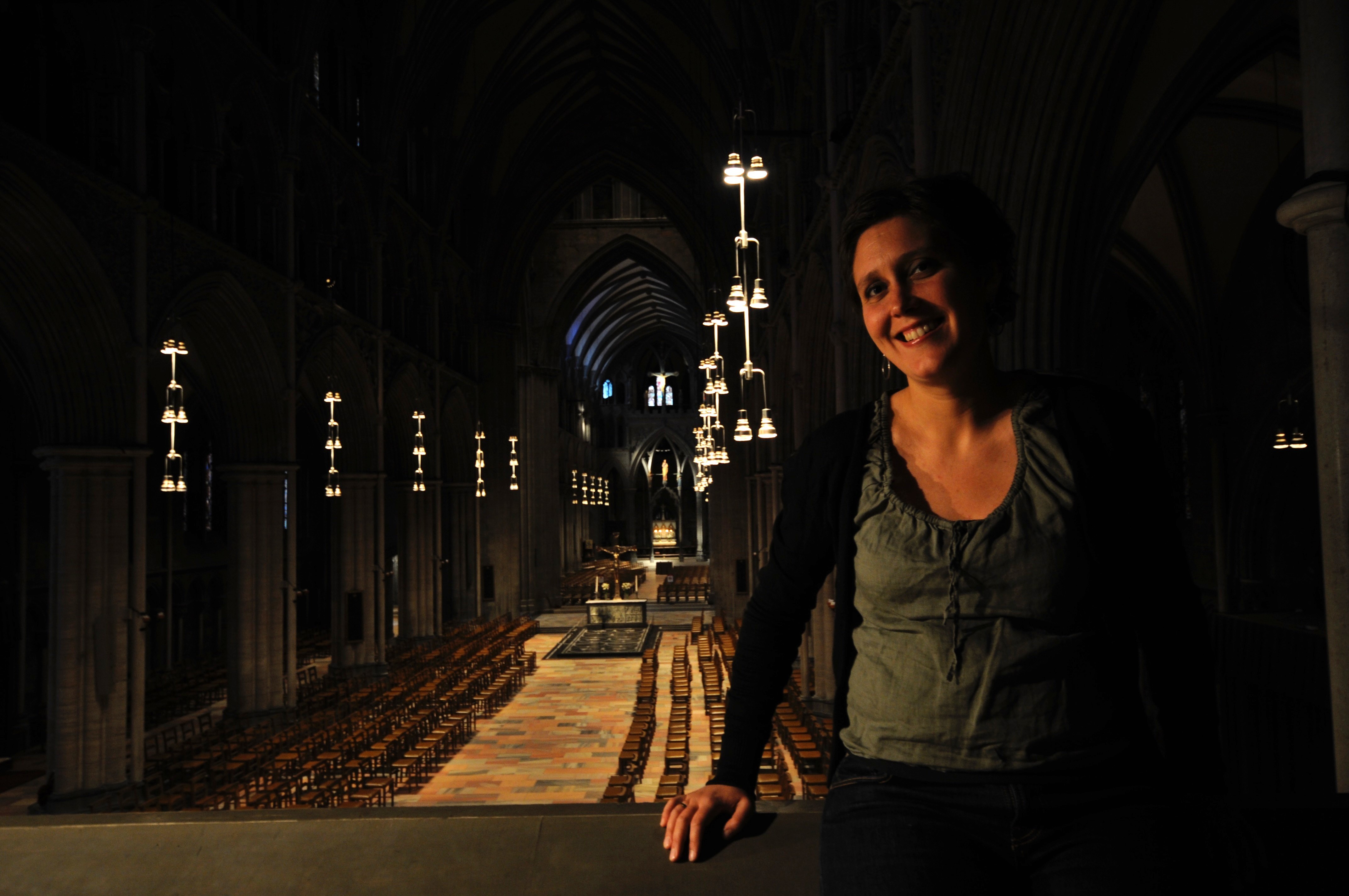 Ung kvinne står på et galleri med et stort kirkerom i bakgrunnen