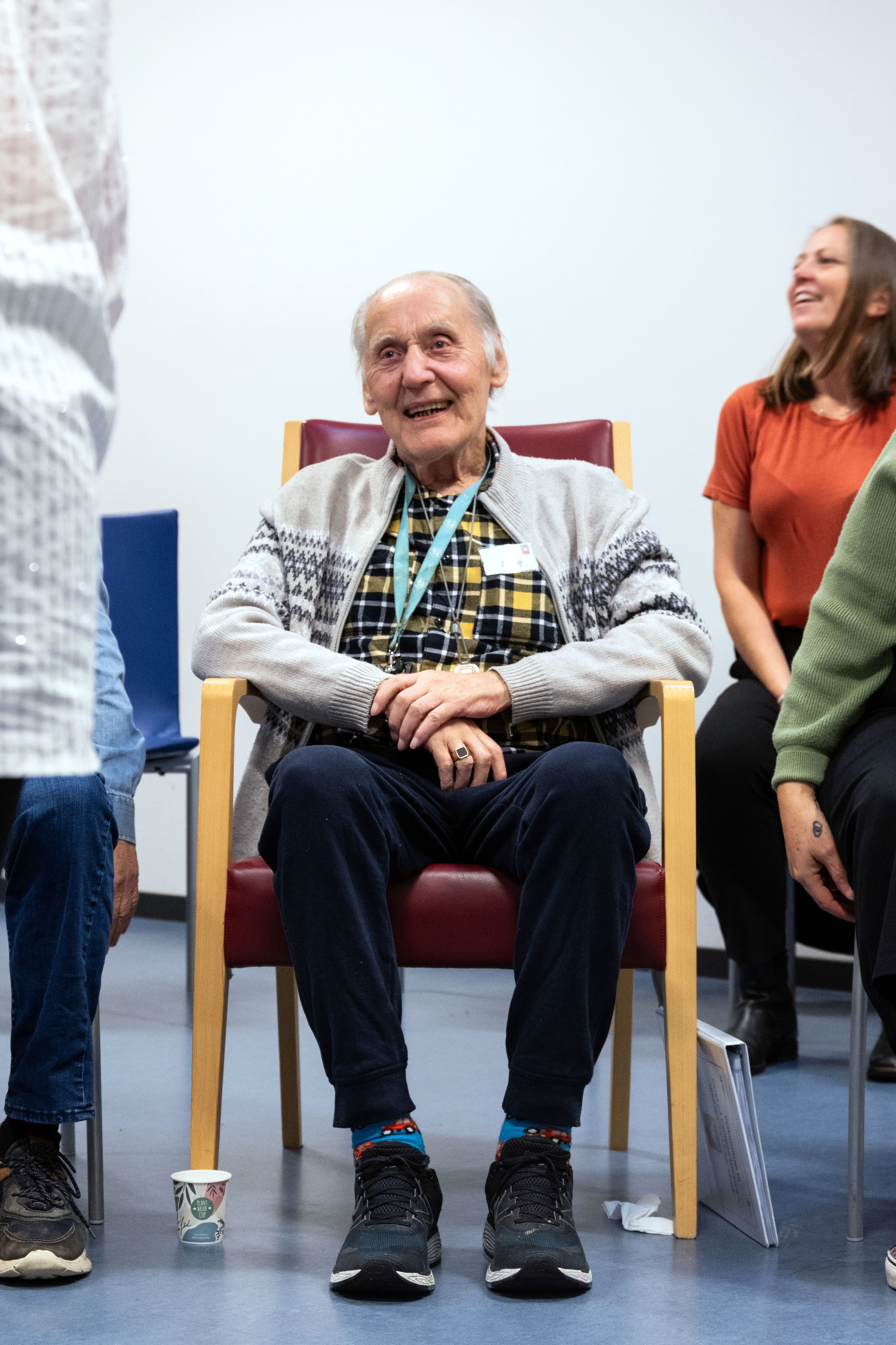 En smilende eldre mann sitter i en stol på en korøvelse.